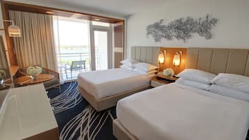 A hotel room with two beds, a desk, a chair, a balcony with a view, and a decorative wall piece.