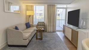 A modern hotel room with a sofa, a small side table, a television, and a glass cabinet. - Hilton Fort Lauderdale Marina (Fort Lauderdale)