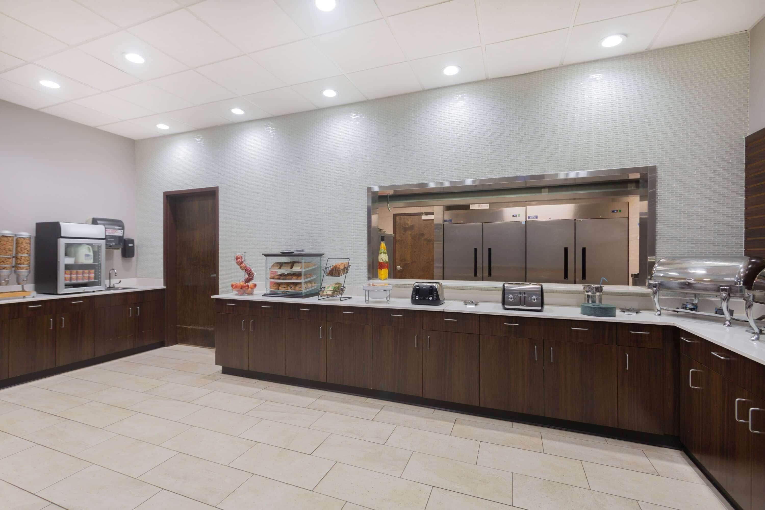 Cozinha moderna com ilha central, equipada com máquina de café, torradeira e espaço para exposição de alimentos.