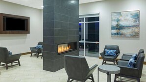 Un área de estar moderna con chimenea empotrada, asientos cómodos y un televisor de pantalla plana grande.