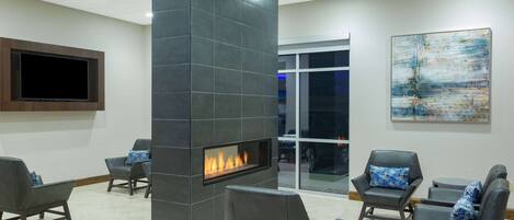 A modern lounge area with a built-in fireplace, comfortable seating, and a large flat-screen TV.