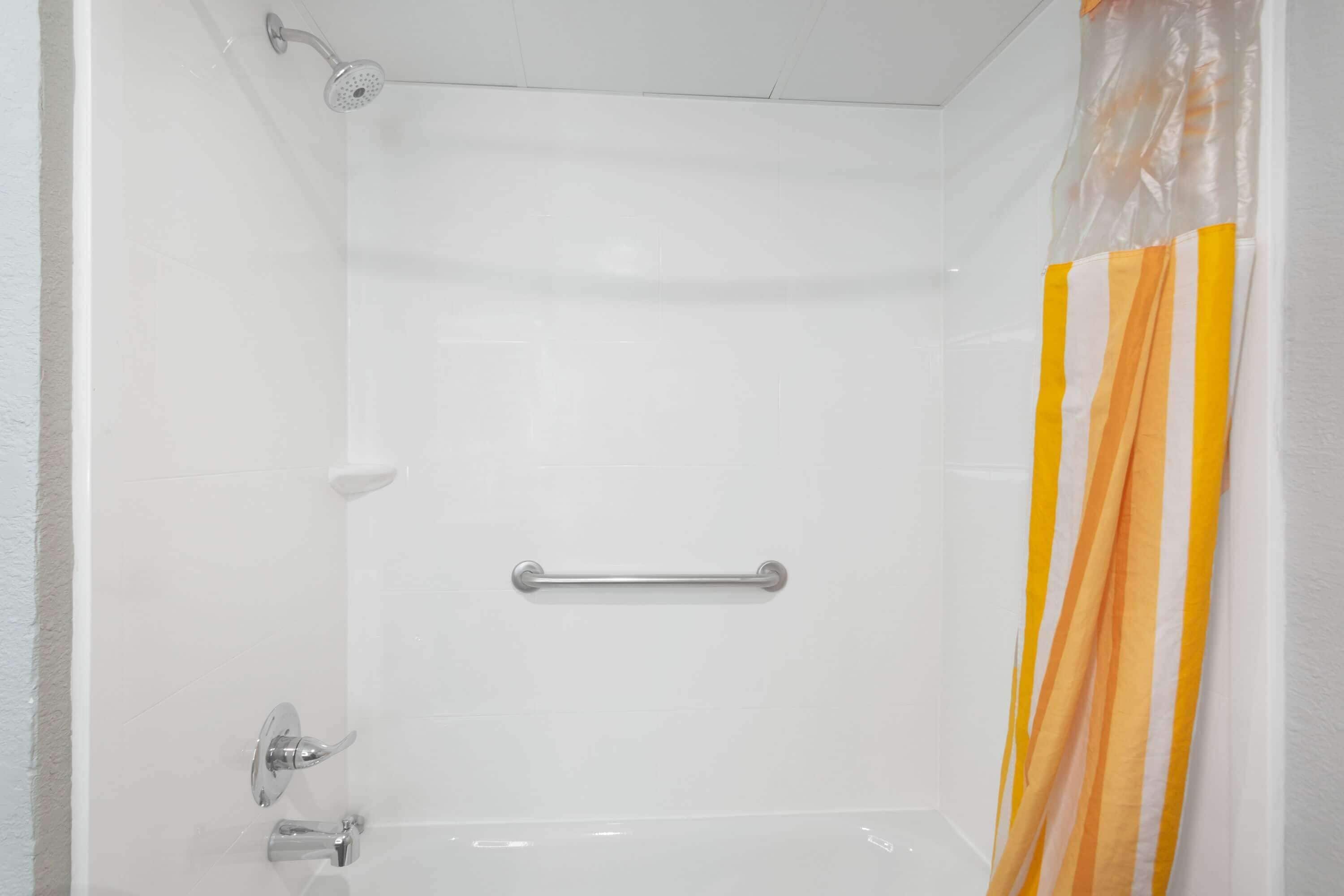 Een douche met een handgreep, douchekop en gordijn.