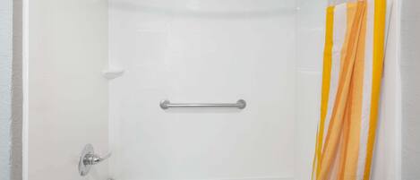 Una ducha con barra de apoyo, cabezal de ducha y cortina.
