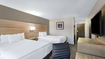 A hotel room with two beds, a TV, a desk, and a chair.
