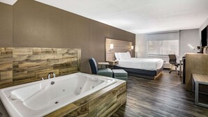 Una habitación de hotel moderna con una bañera grande, una cama, un escritorio y una silla.