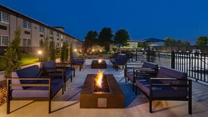 Un espacio al aire libre con fogones y sillones de descanso, con vistas a una piscina y un complejo de edificios.
