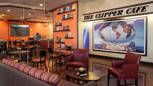 A cafe interior with a menu board, seating, and a large globe artwork. - Airtel Plaza Hotel (Van Nuys)