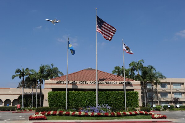 Airport Plaza Hotel and Conference Center features a modern flat facade with a red-tiled roof and landscaped front.