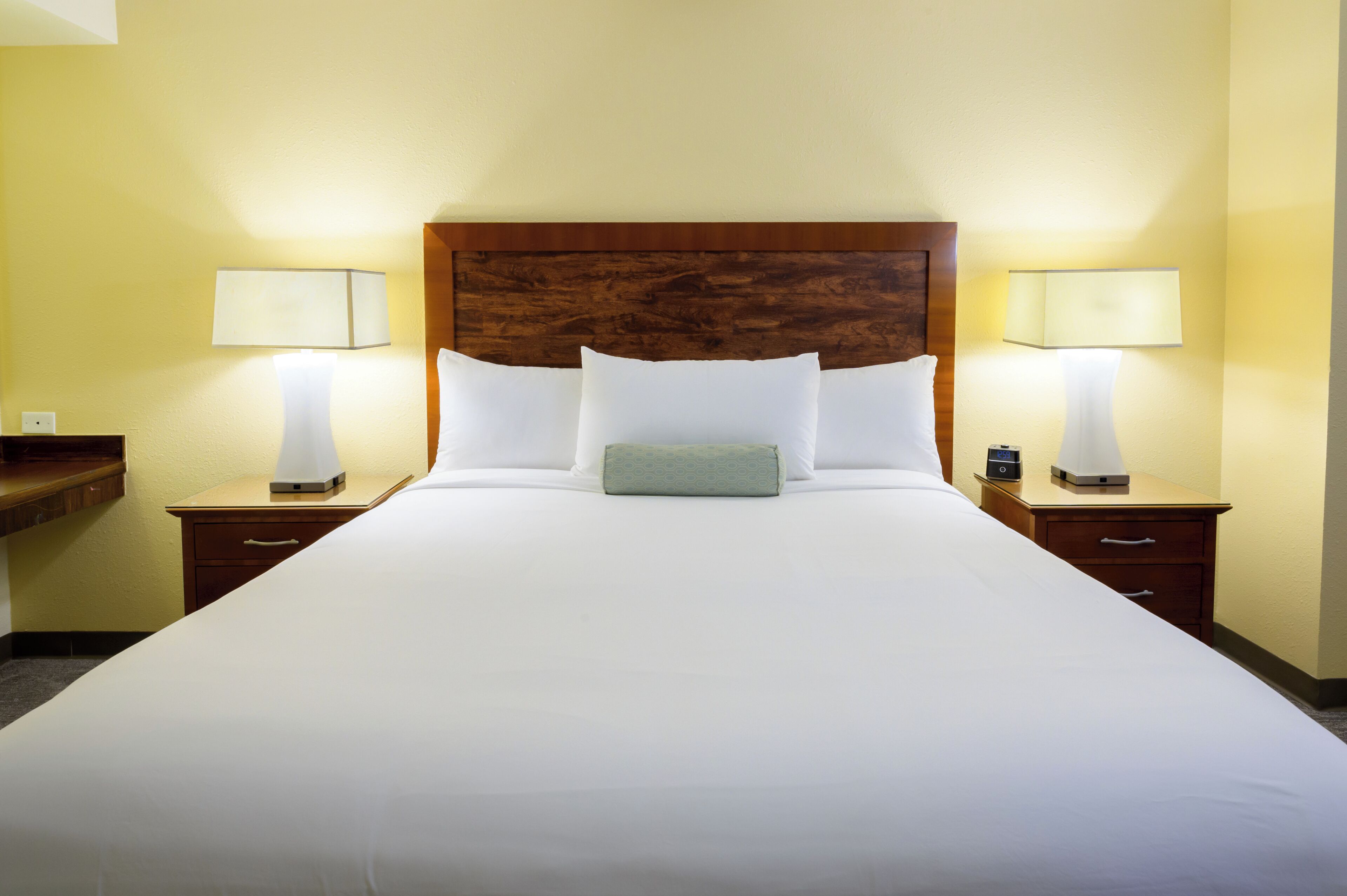 A hotel room with a large bed, two bedside tables with lamps, and a wooden headboard.