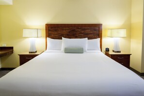 Una habitación de hotel con una cama grande, dos mesitas de noche con lámparas y un cabecero de madera.