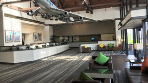 A spacious lobby with a large airplane model suspended above the reception desk, modern furniture, and large windows allowing natural light. - Airtel Plaza Hotel (Van Nuys)