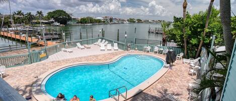 A swimming pool with lounge chairs and a view of a marina.