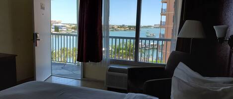 Ein Hotelzimmer mit Balkon und Blick auf einen Yachthafen und Gebäude.