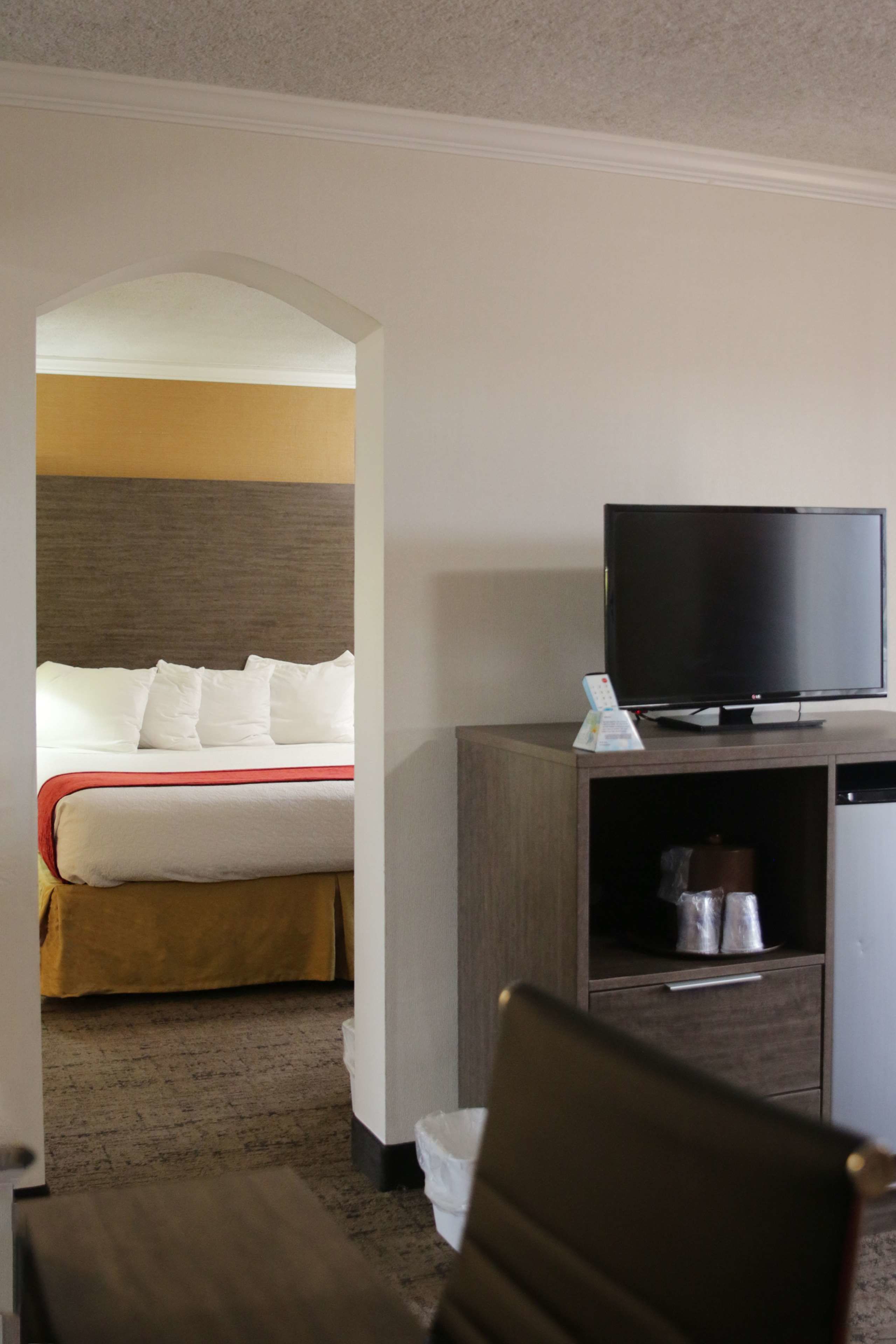 Une chambre d’hôtel avec un lit, un téléviseur posé sur une commode en bois et une petite table.