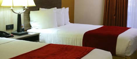 Een hotelkamer met twee bedden, een nachtkastje met een lamp en een telefoon.