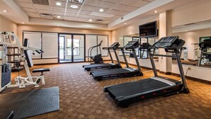 A gym with treadmills, weight machines, and a mirrored wall.