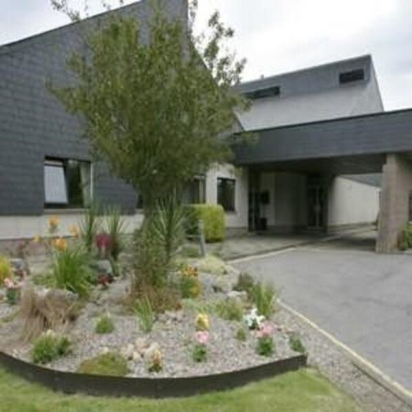 Un edificio moderno con techo plano y jardín ajardinado con diversas plantas y flores.