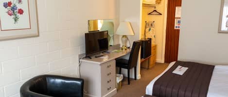 Een hotelkamer met een bureau, stoel en twee bedden.
