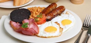 Un plato con huevos, salchichas, frijoles y tocino.