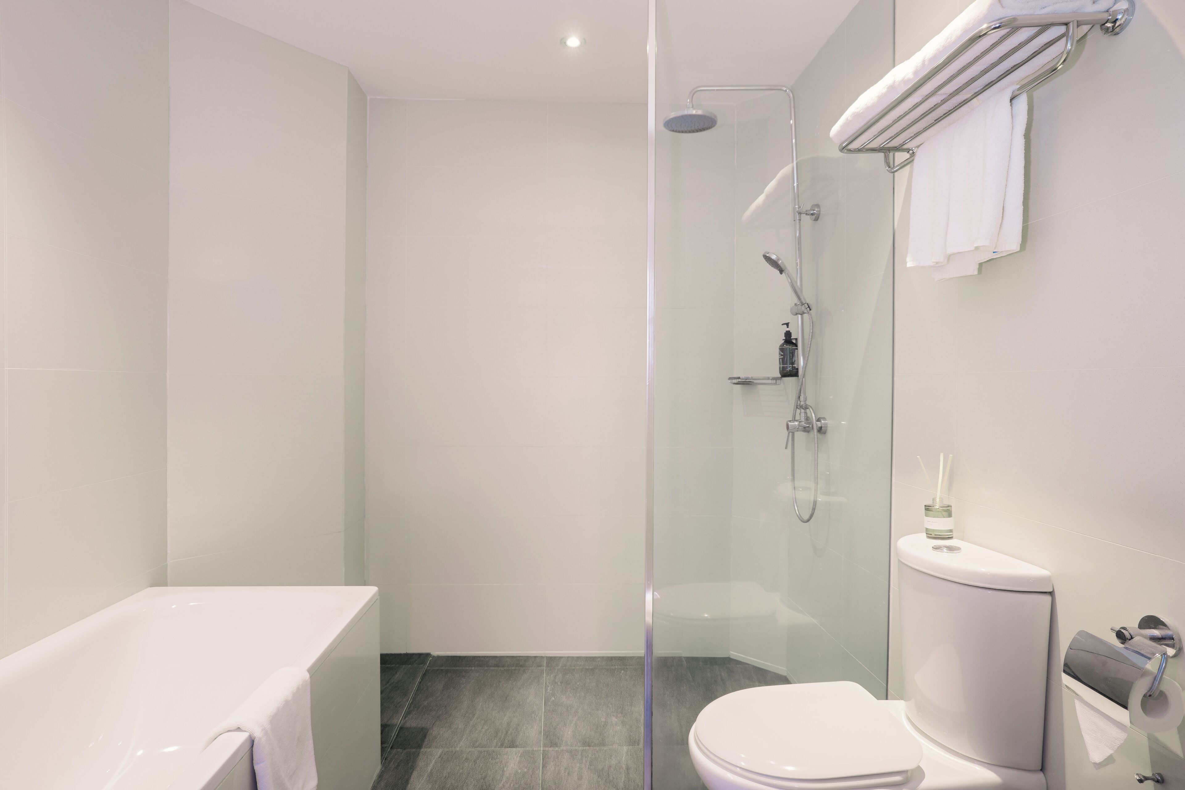 Un baño moderno con ducha de vidrio, una bañera blanca y un inodoro.