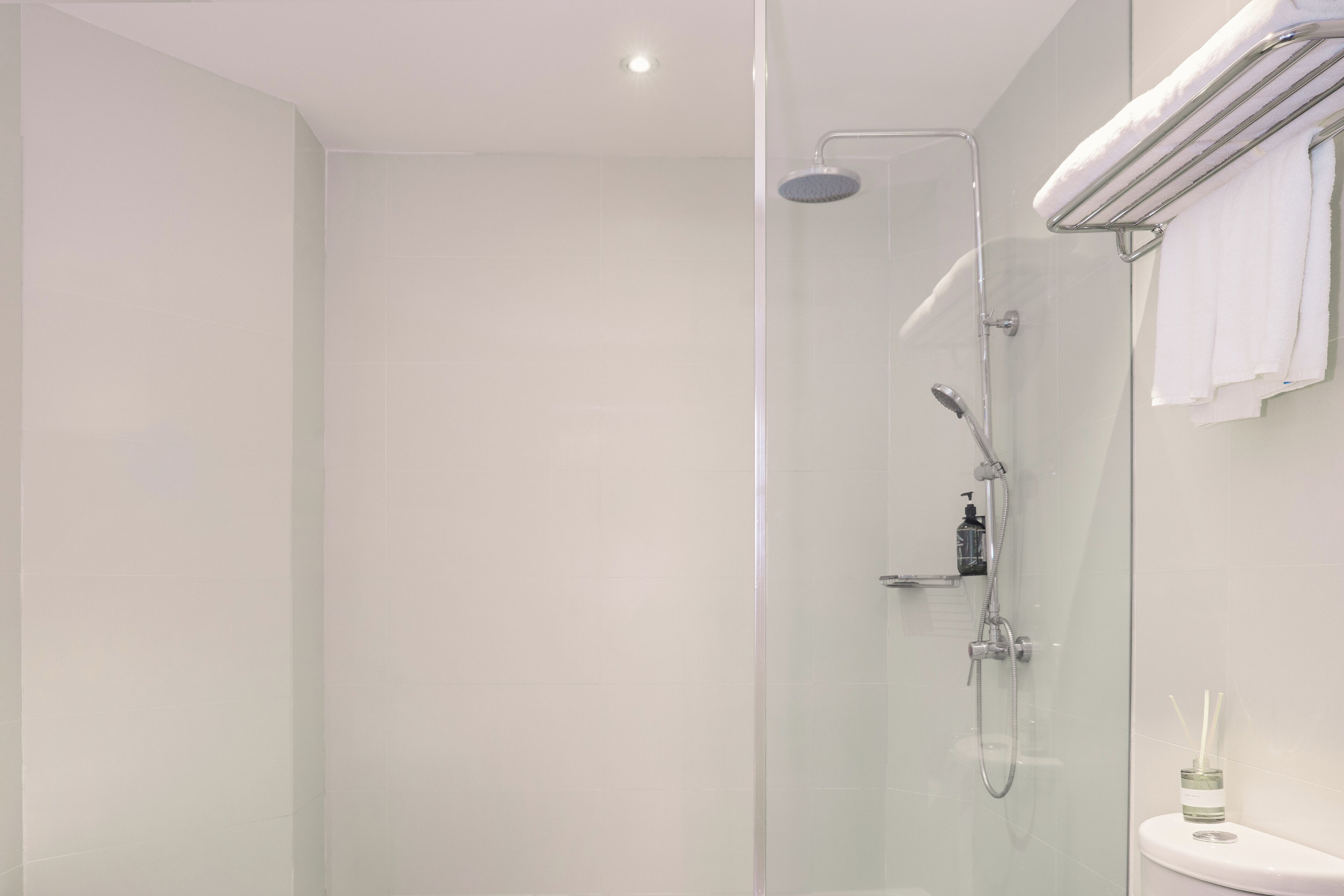 A modern bathroom with a glass-enclosed shower, a white toilet, and a towel rack.