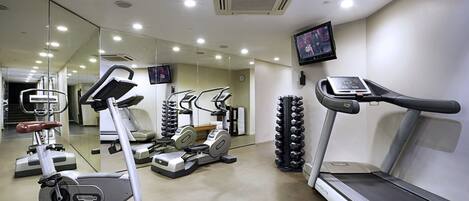 A gym with cardio machines, a treadmill, and a mirrored wall.