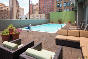 A rooftop pool area with lounge chairs and potted plants.