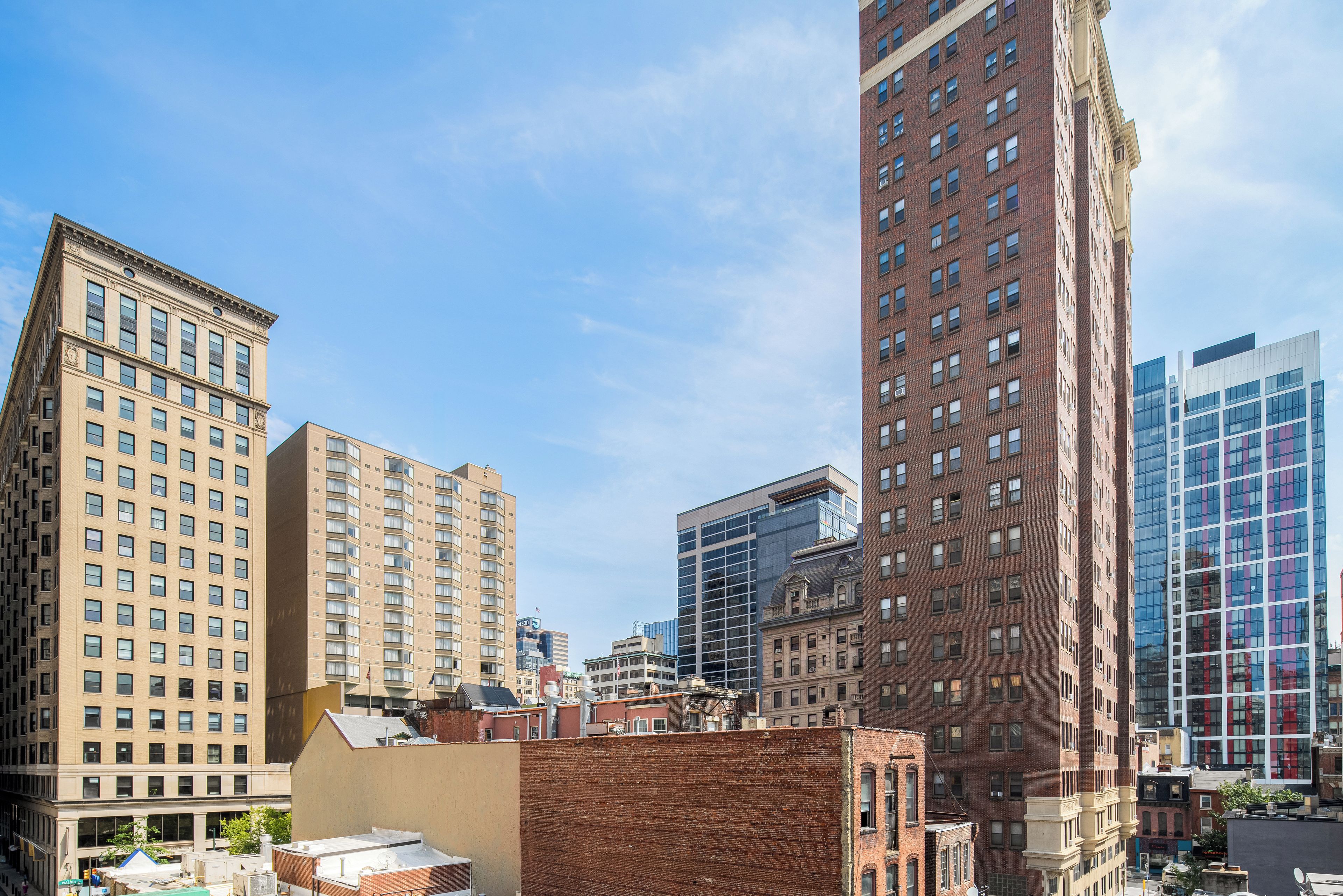 A cityscape with multiple high-rise buildings, including a mix of older brick structures and modern glass facades.