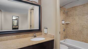 A bathroom with a sink, mirror, toilet, and bathtub.