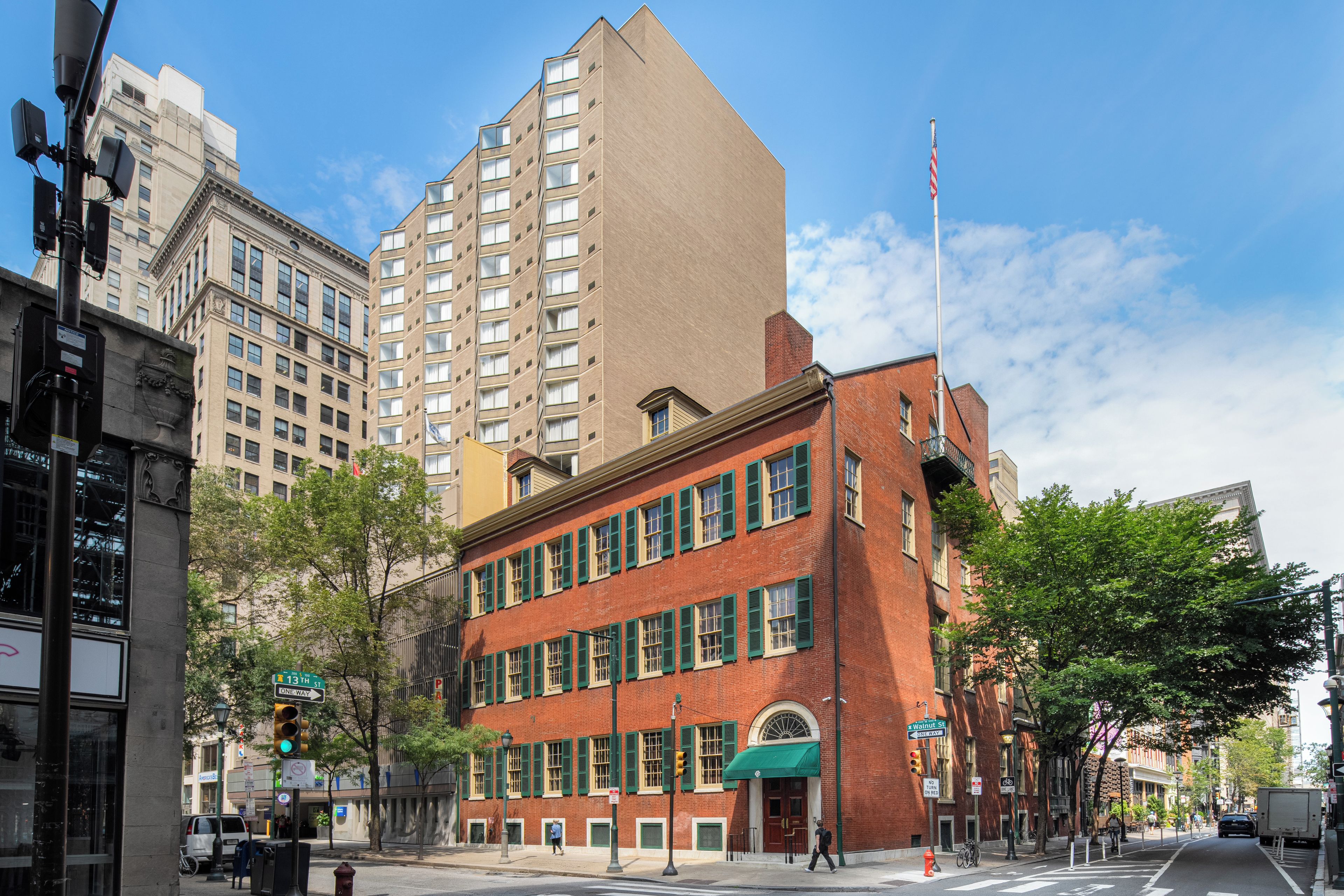A street view with a red brick building, a modern high-rise, and a clear sky.