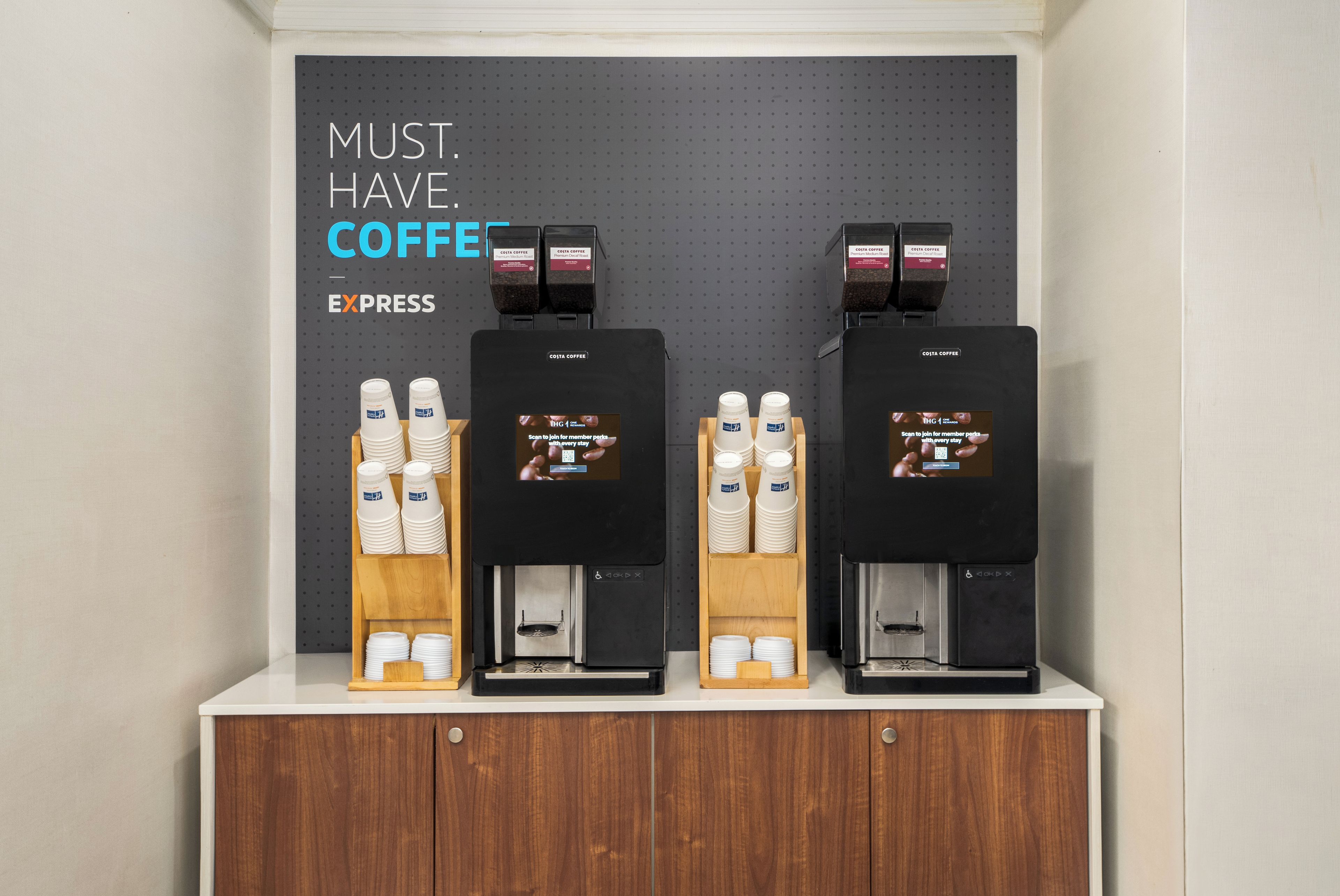 Un espace dédié au café, équipé de quatre machines à expresso et d’un panneau indiquant : « EXPRESSO : INDISPENSABLE ».