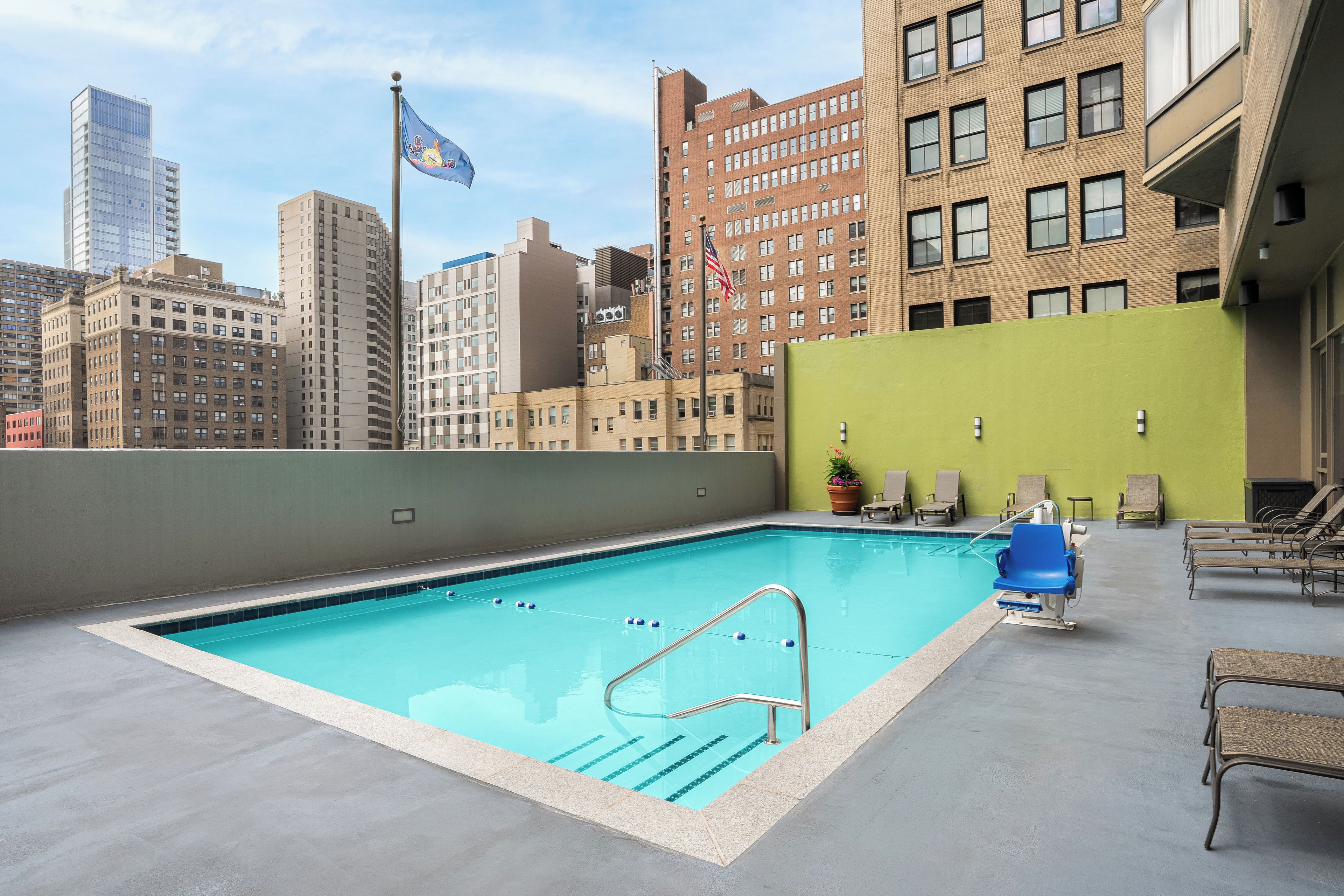 A rooftop pool with a clear view of surrounding buildings, including a flagpole with a flag.