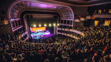 A large indoor auditorium with tiered seating, a stage with a 'LOVE' backdrop, and a crowd of attendees.