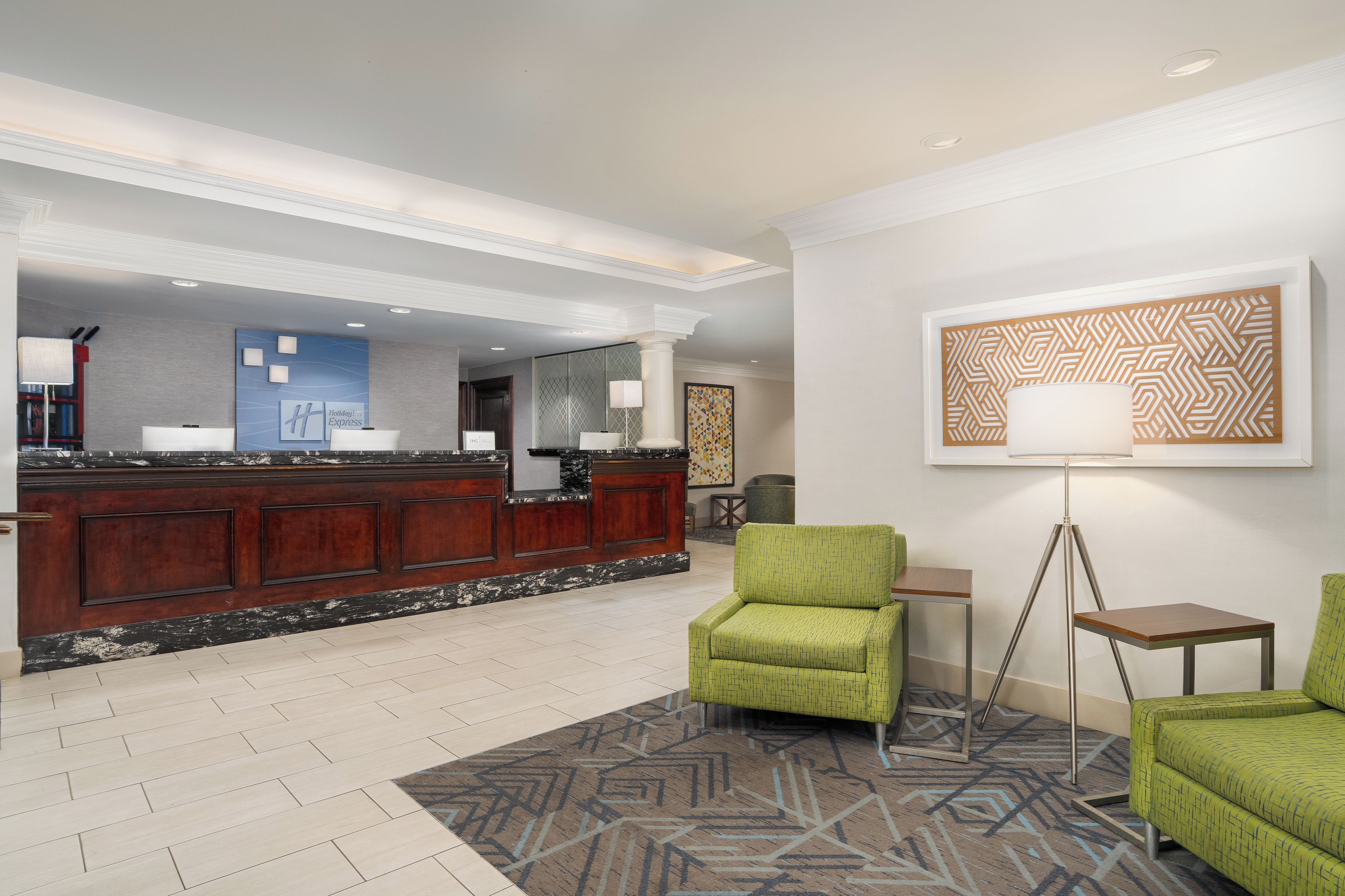 A hotel lobby with a reception desk, seating area, and artwork on the walls.
