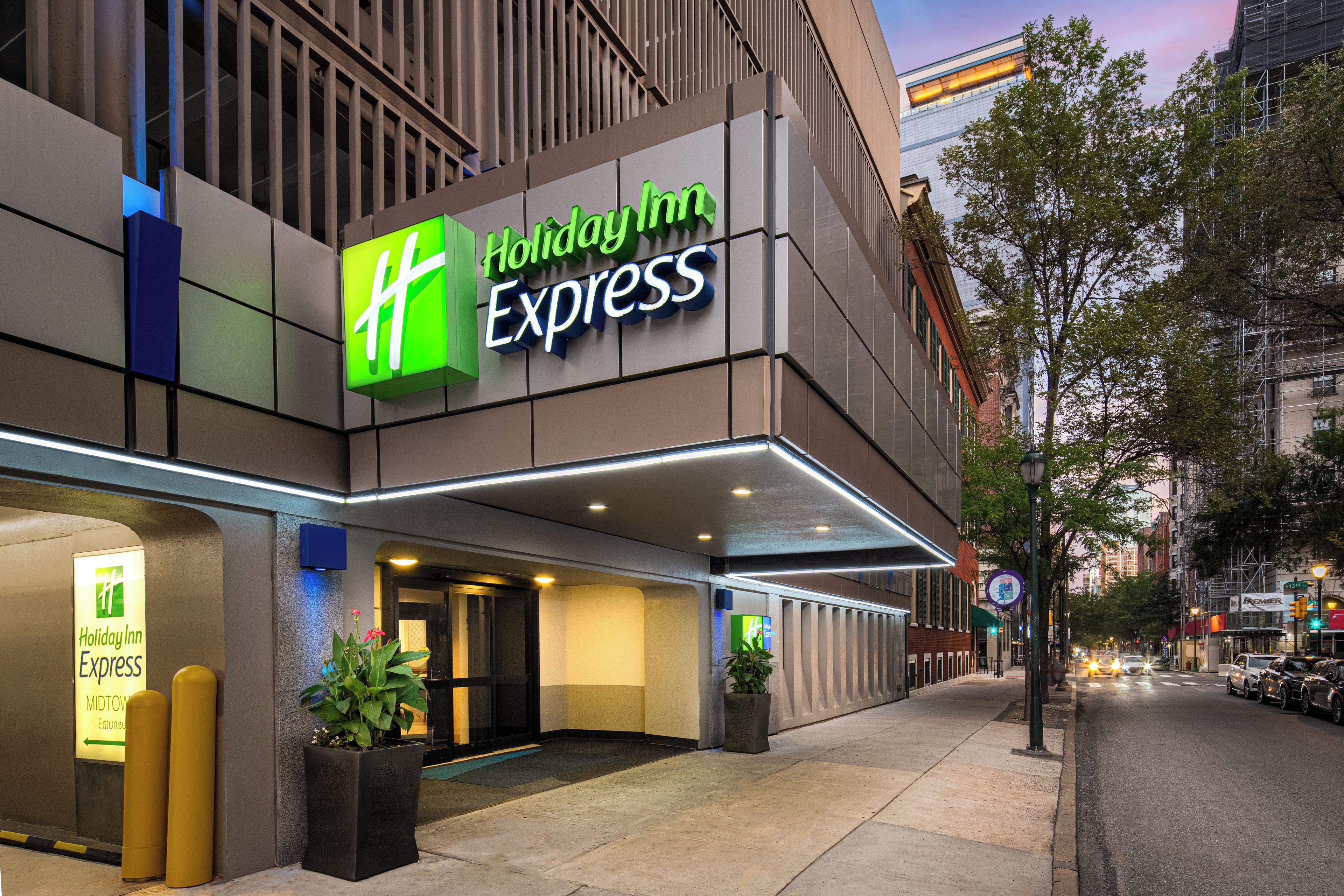 A Holiday Inn Express building with a modern facade, large entrance, and potted plants.