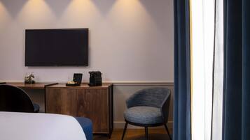 Une chambre d’hôtel comprenant un lit, un bureau avec un téléviseur à écran plat, une chaise et un petit meuble de rangement.