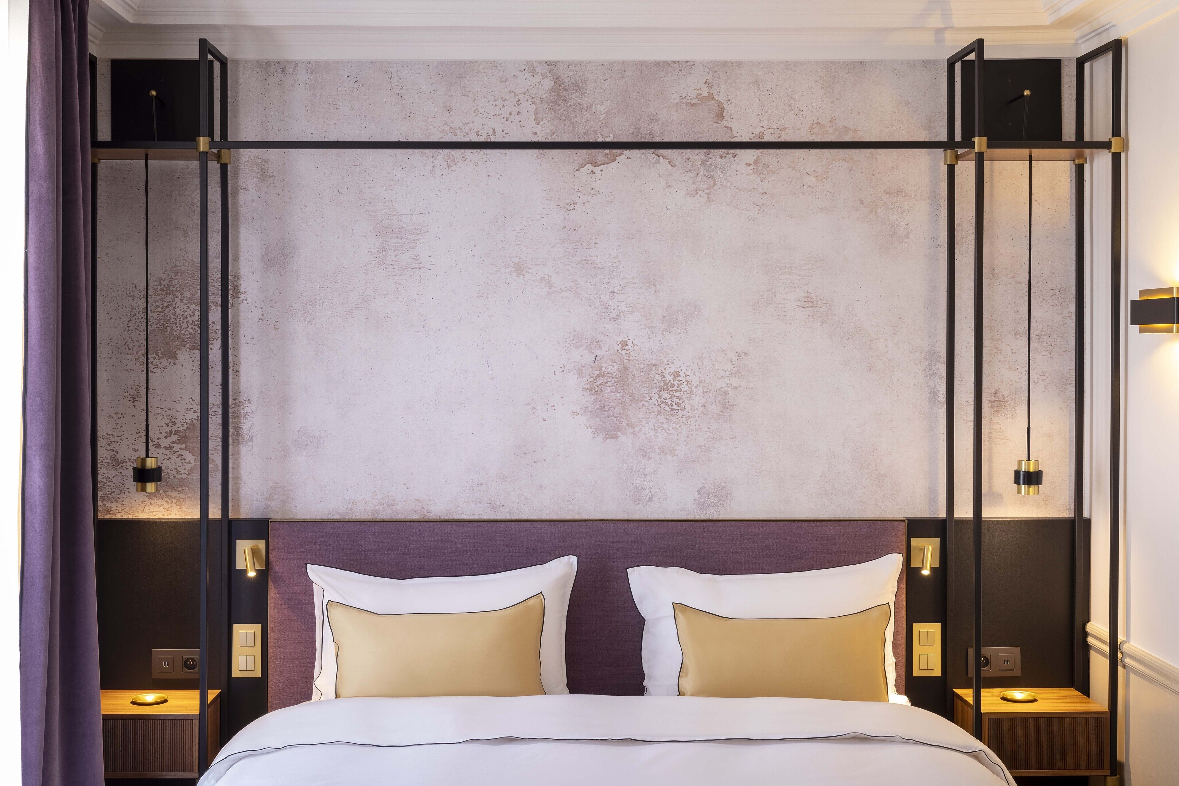 Une chambre d’hôtel moderne avec un grand lit, deux tables de chevet et un mur à texture.