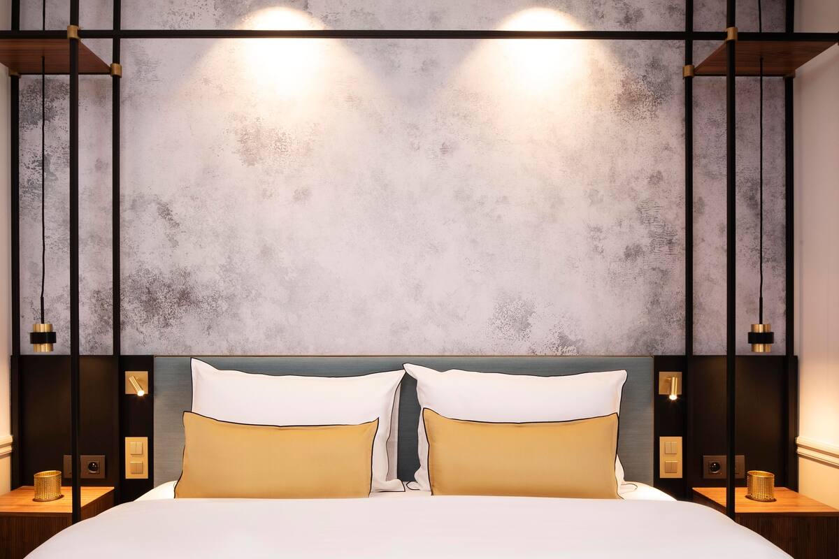 A modern bedroom with a large bed, two bedside tables, and a textured wall.