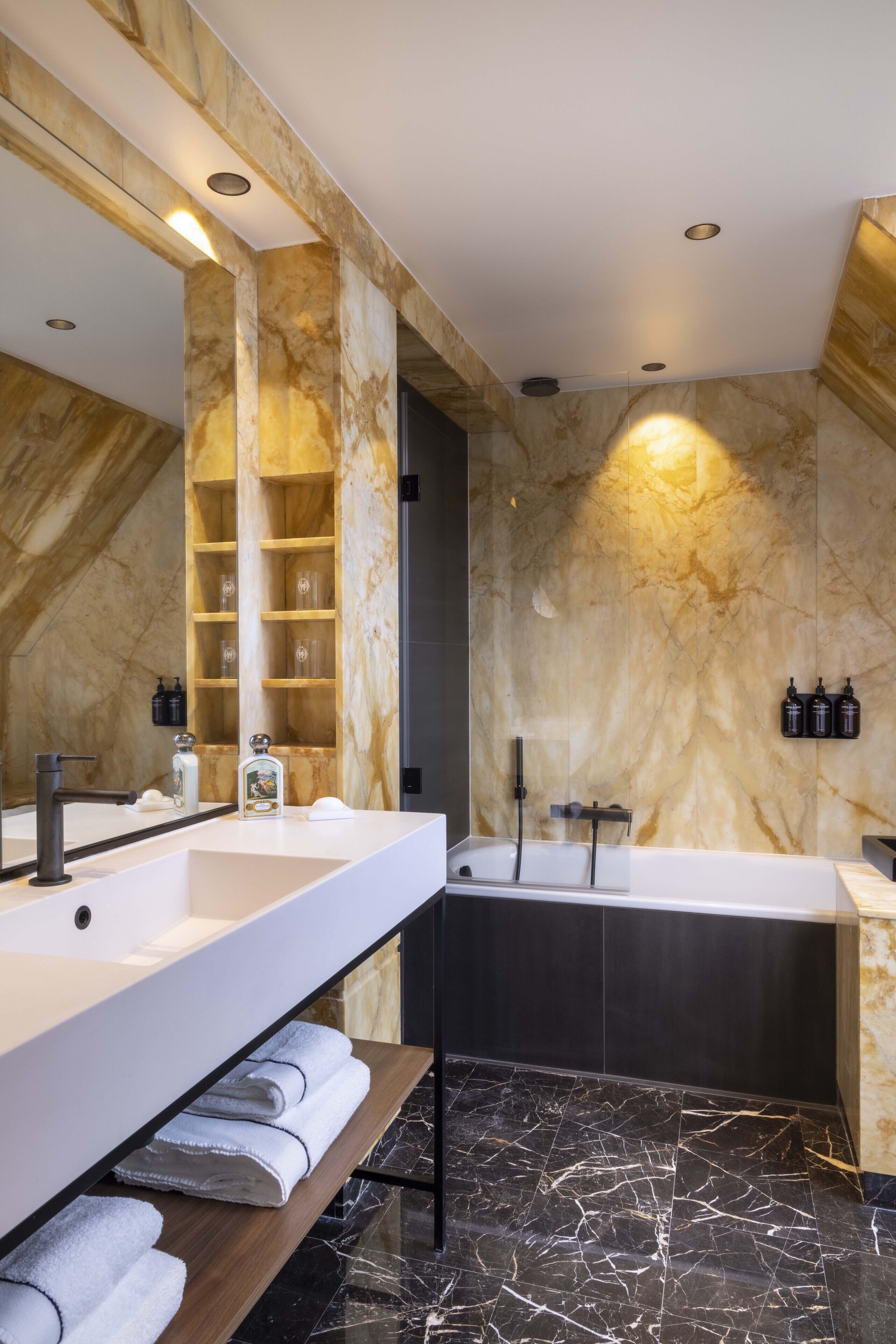 A modern bathroom with two sinks, a bathtub, and a large mirror.