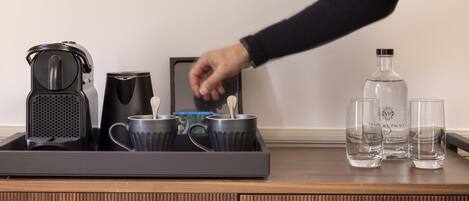Un plateau contenant une cafetière, deux tasses et une bouteille d’eau, posé sur une surface en bois.