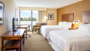 Ett hotellrum med två sängar, ett skrivbord, en stol och en TV.