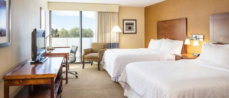 Une chambre d’hôtel avec deux lits, un bureau, une chaise et un téléviseur.