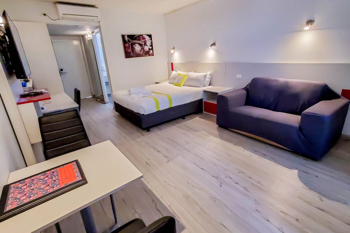 Une chambre d’hôtel moderne équipée d’un lit, d’un canapé, d’un bureau et d’une chaise.