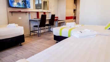 Une chambre d’hôtel avec deux lits, un bureau, des chaises, une télévision et une armoire.