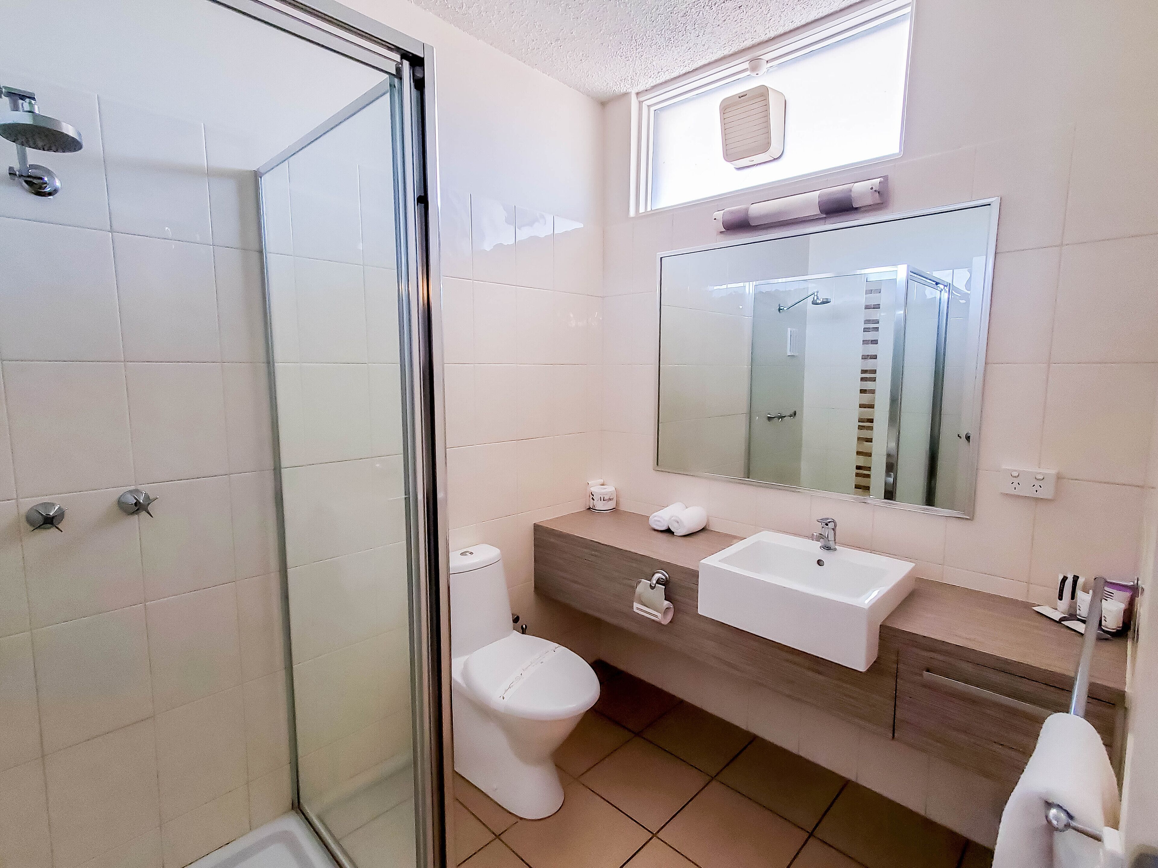 Ein modernes Badezimmer mit Duschkabine aus Glas, einer weißen Toilette, einem Waschbecken mit Spiegel und einem Handtuchhalter.