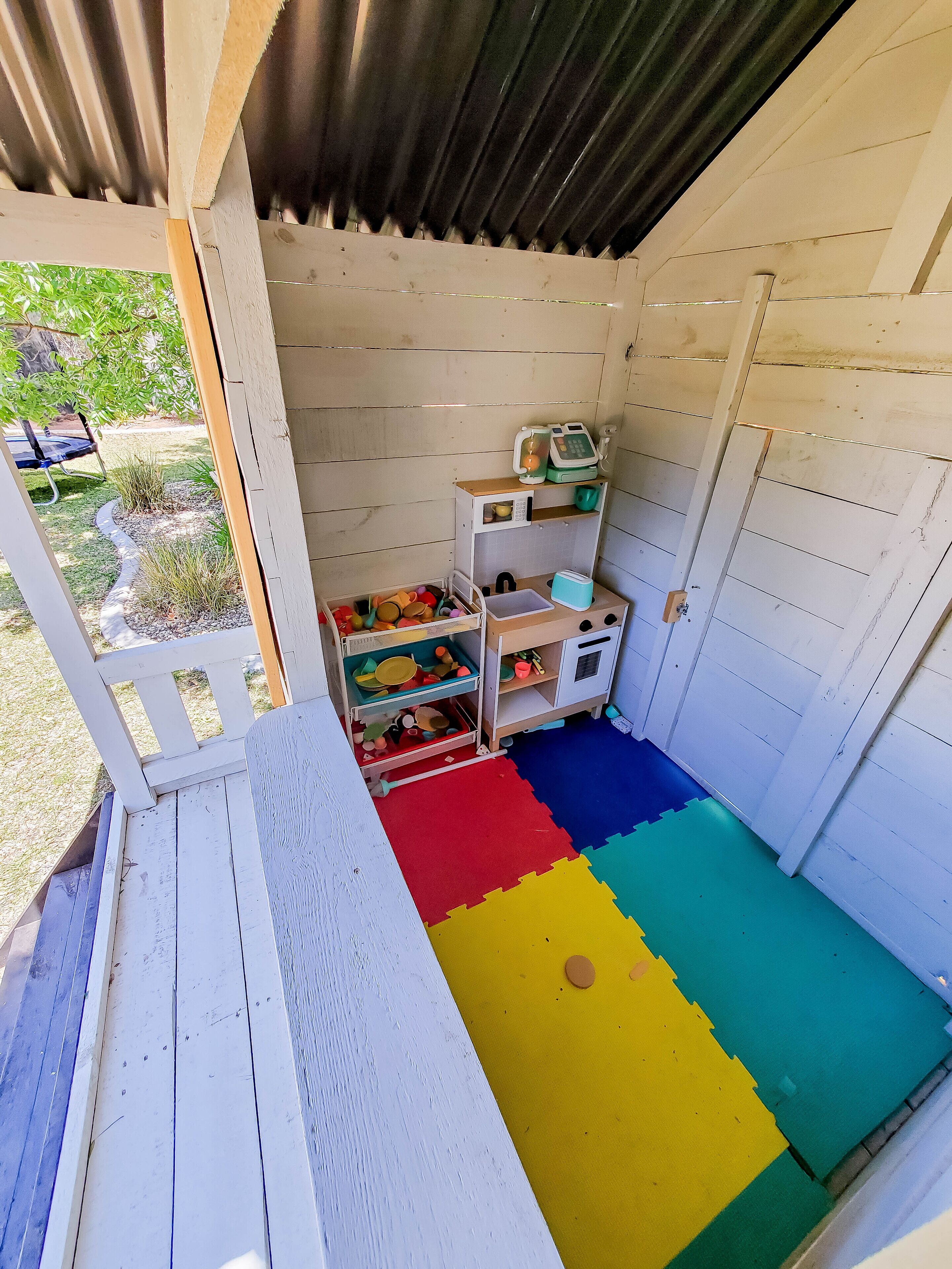 A children's playroom with a play mat, storage units, and a small table.