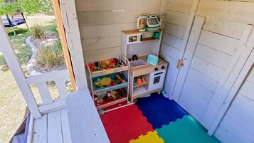 A children's playroom with a play mat, storage units, and a small table.