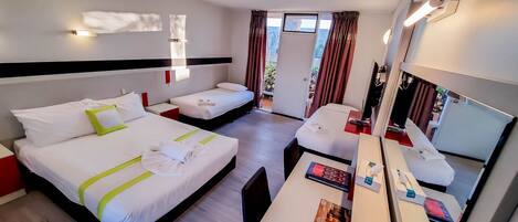 A hotel room with two beds, a desk, a mirror, and a window with curtains.