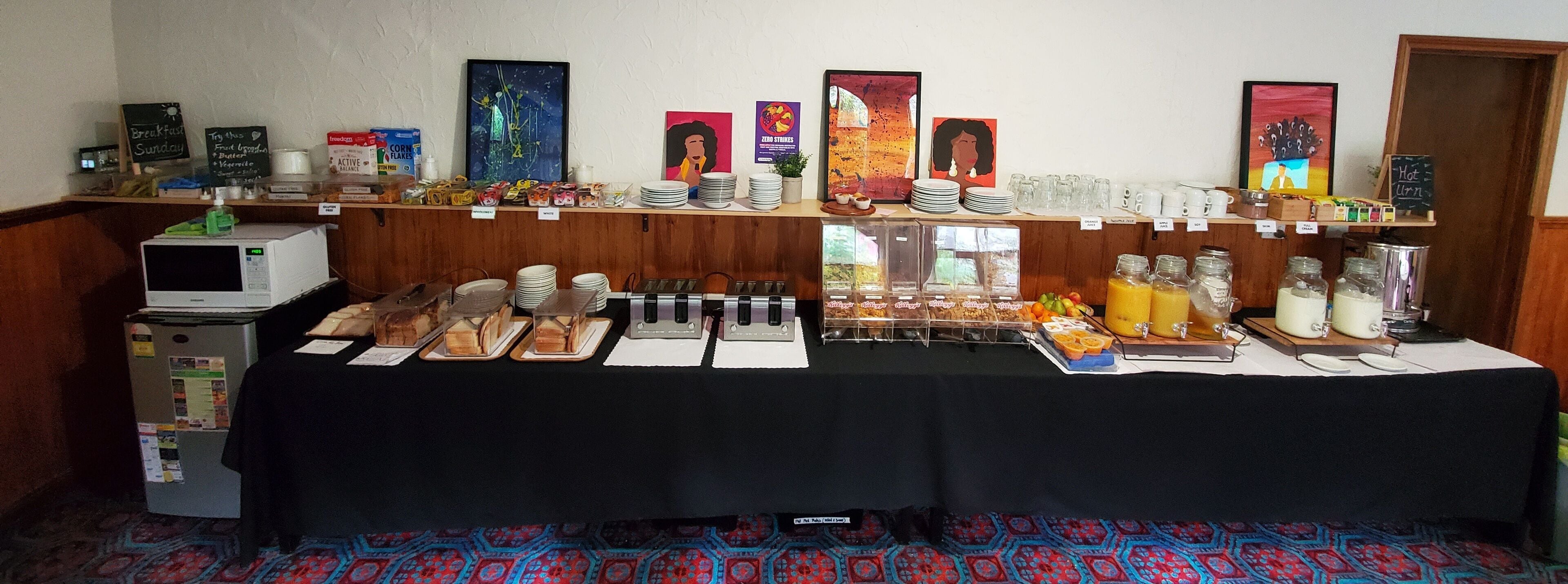 A breakfast buffet setup with various food items, plates, and serving utensils.