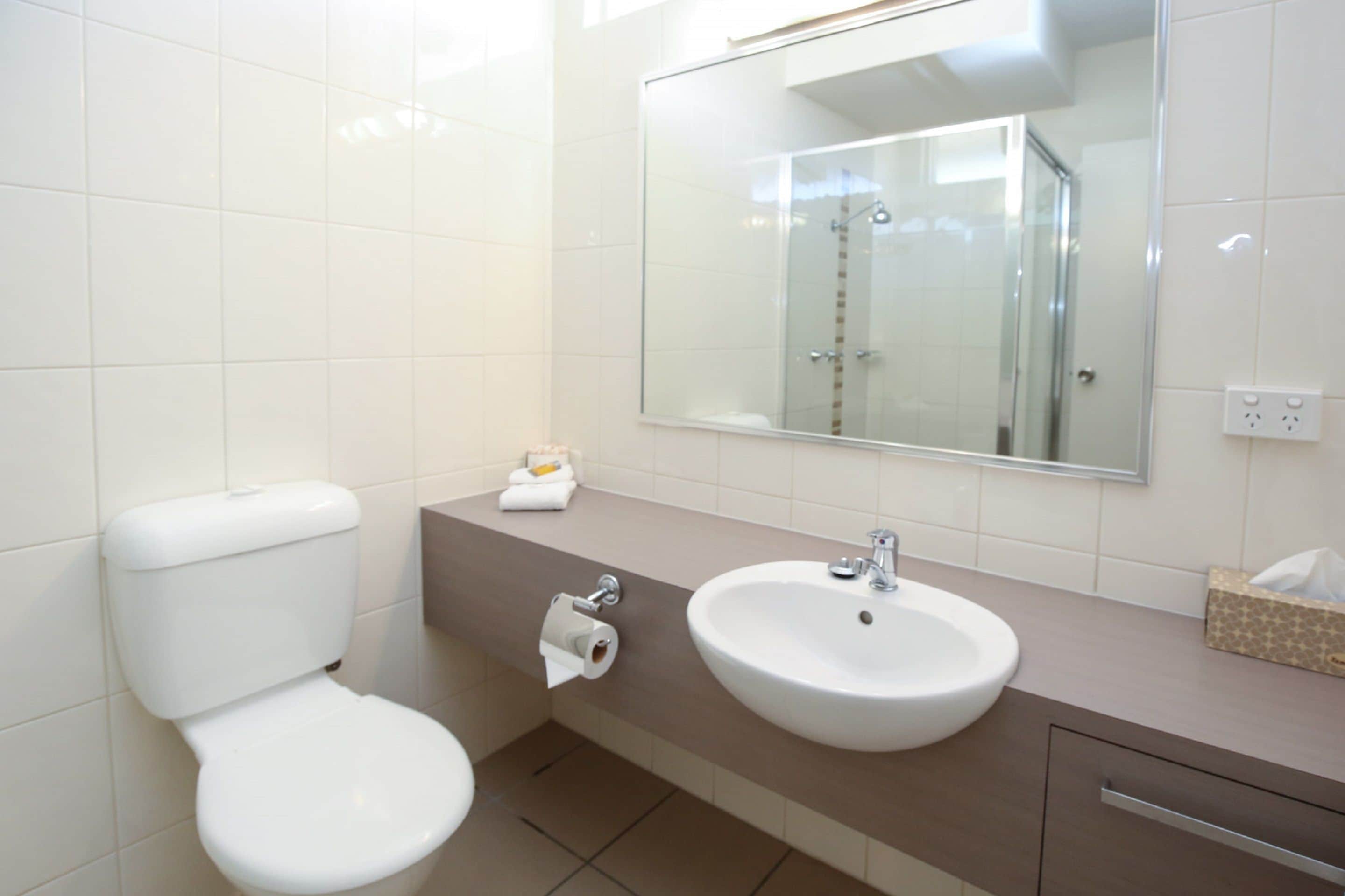 Un baño moderno con inodoro, lavamanos y espejo.